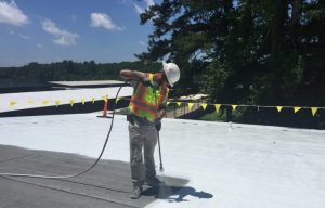 Curtis Construction roofer applying coating to roof