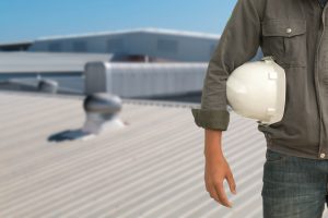 man holding white hard hat while standing on roof