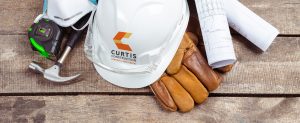 Curtis Construction hard hat, gloves, hamer, measuring tape and house plans